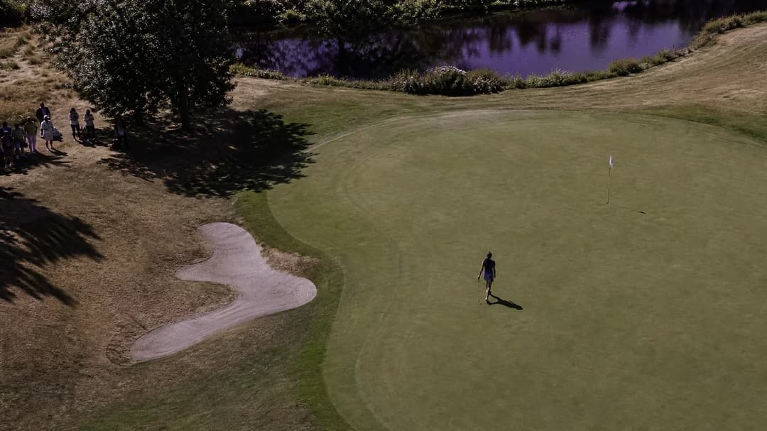 A bird's-eye view of a golf course with Jenny Shin approaching the 18th hole, highlighting her triumph in the Women's Scottish Open.
