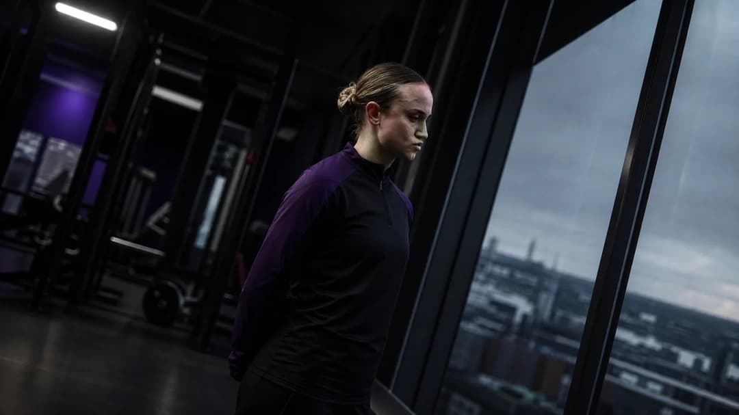 Martha Thomas standing in a training facility, looking out the window.
