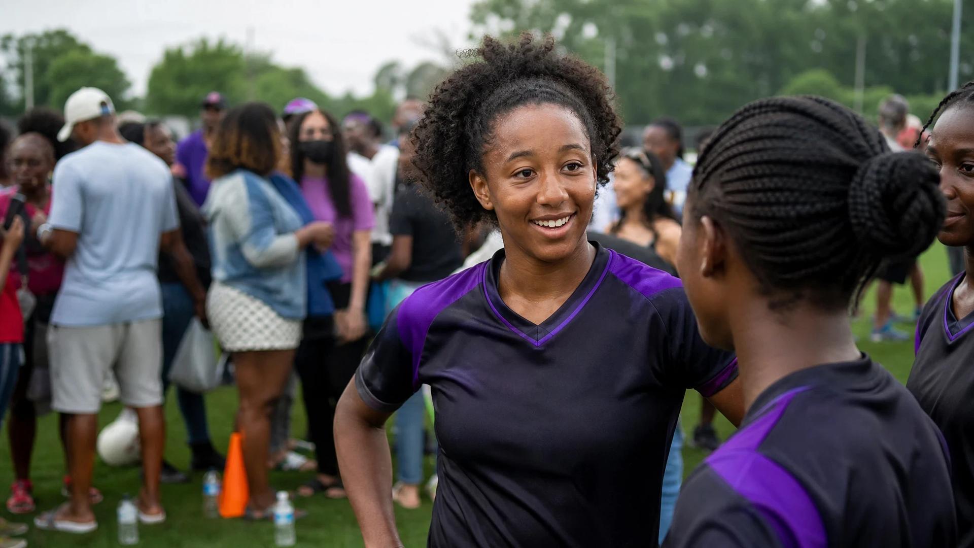 Amandine Pierre-Louis interacting at the Montreal Roses training ground, surrounded by fans and teammates.