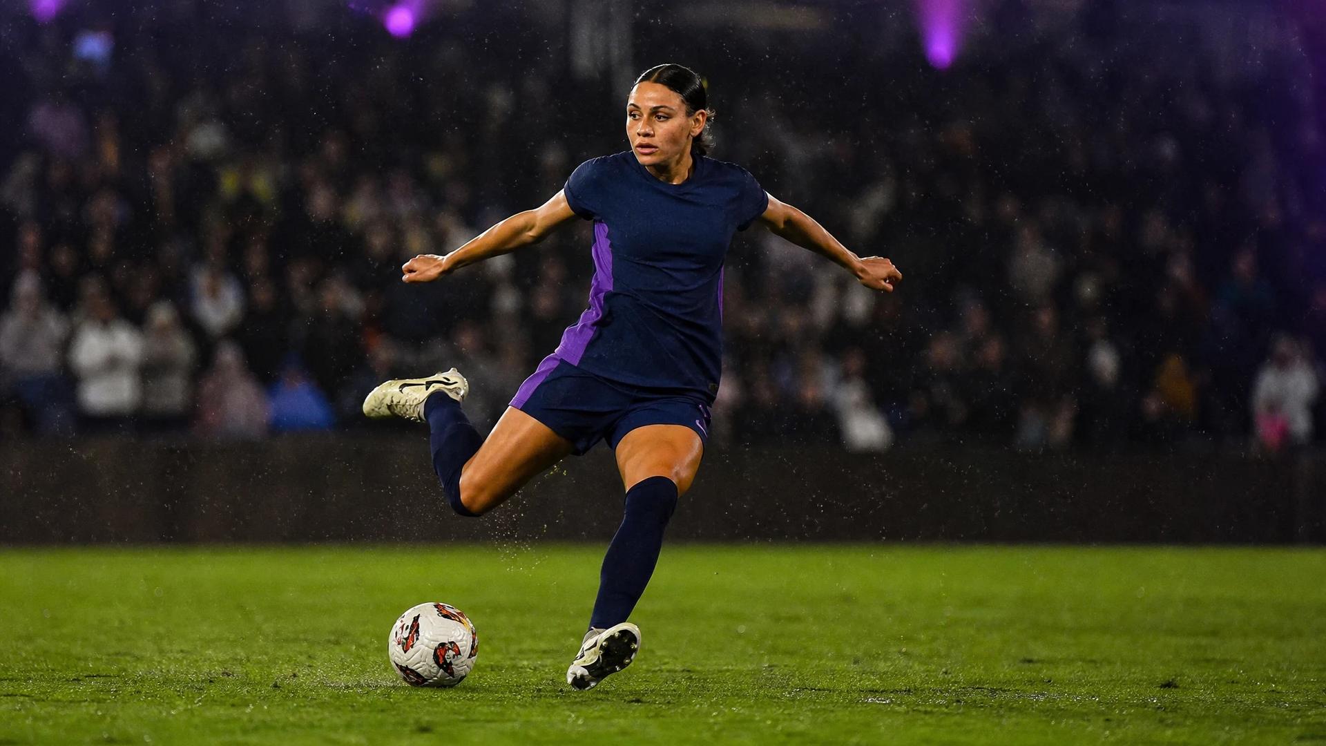 Trinity Rodman striking the ball in a soccer match amidst a vibrant stadium atmosphere.