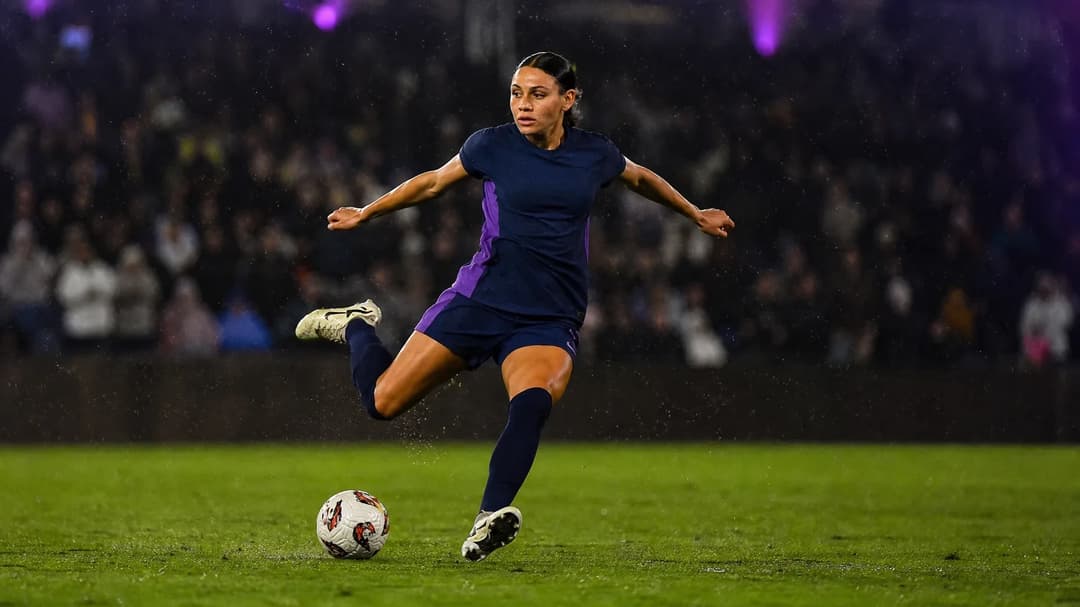 Trinity Rodman striking the ball in a soccer match amidst a vibrant stadium atmosphere.