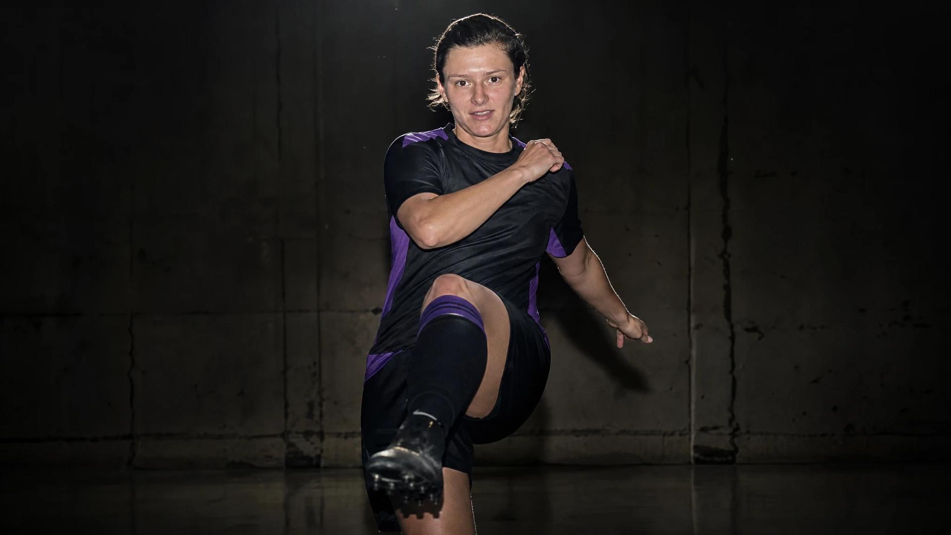 A close-up of Danielle Cox, an English football defender, in a training facility, poised for action under a spotlight.