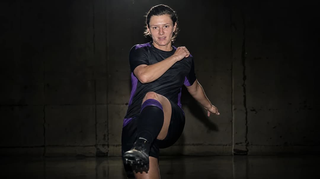 A close-up of Danielle Cox, an English football defender, in a training facility, poised for action under a spotlight.