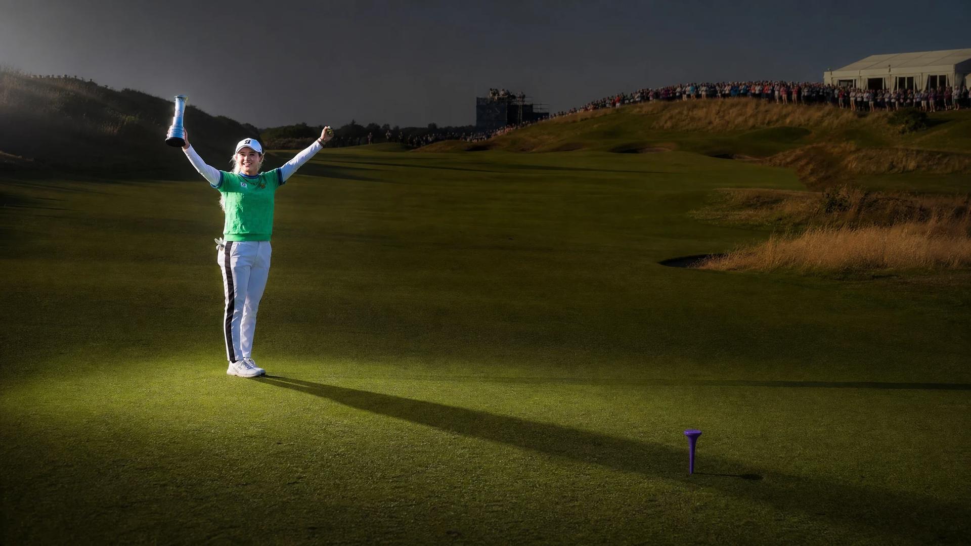 Golfer Shiho Kuwaki celebrating her victory on a lush golf course.