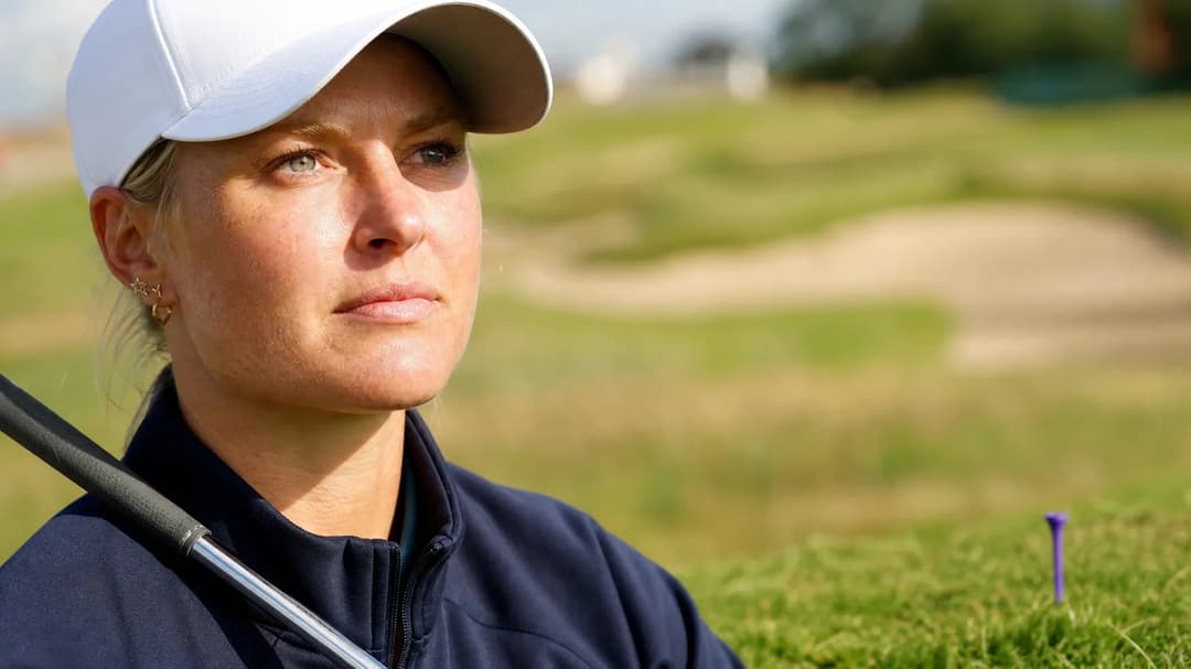 Anna Nordqvist on a golf course, deep in thought with a golf club resting on her shoulder.