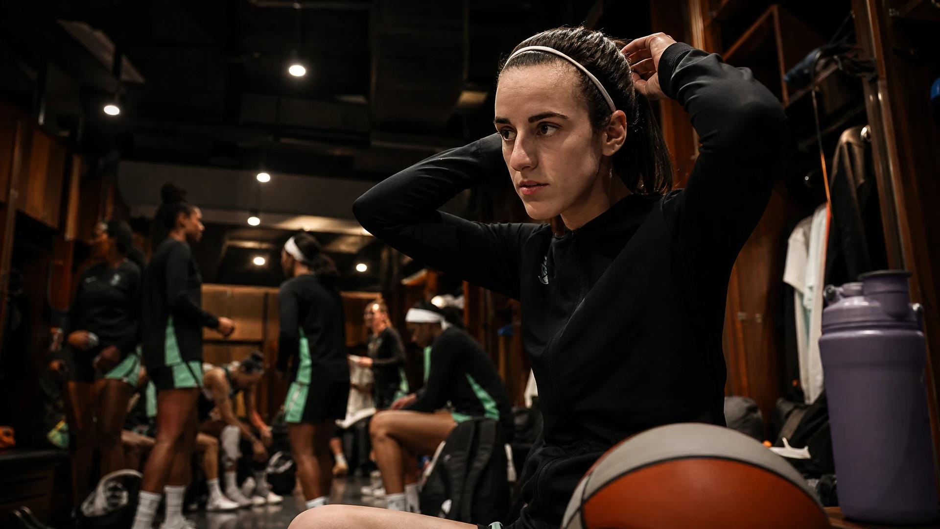 A female basketball player preparing in a locker room before a game.