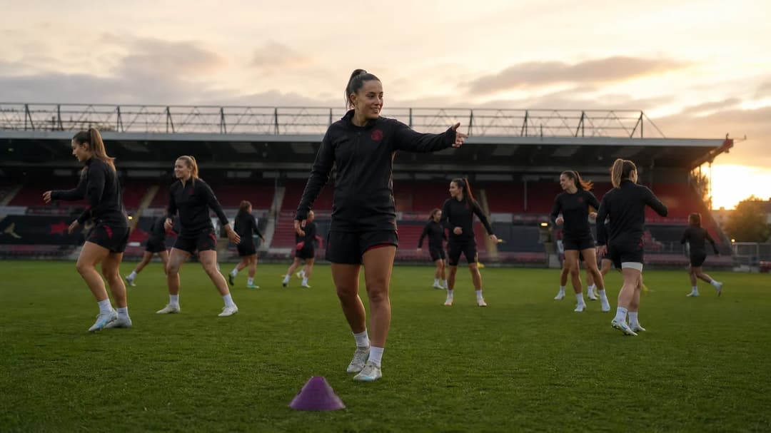 A training session of the Manchester United Women’s team at Old Trafford, with players in motion and a violet training cone on the pitch.
