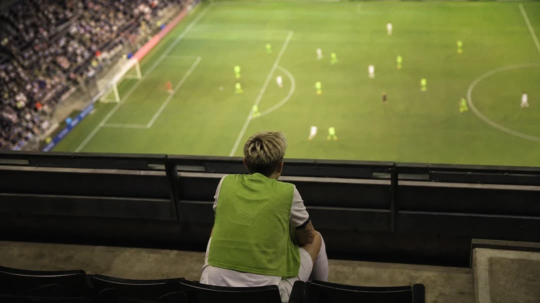 A top-down view of Jess Fishlock sitting on the bench, reflecting during a match.