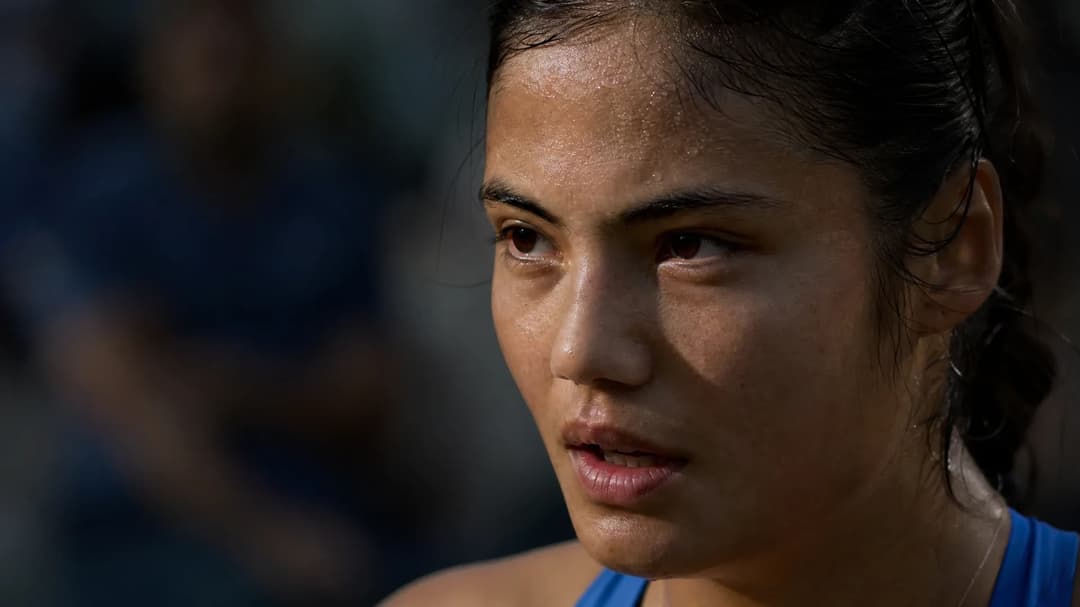 An extreme close-up of Emma Raducanu's face, showing her emotional expression during a moment of reflection.