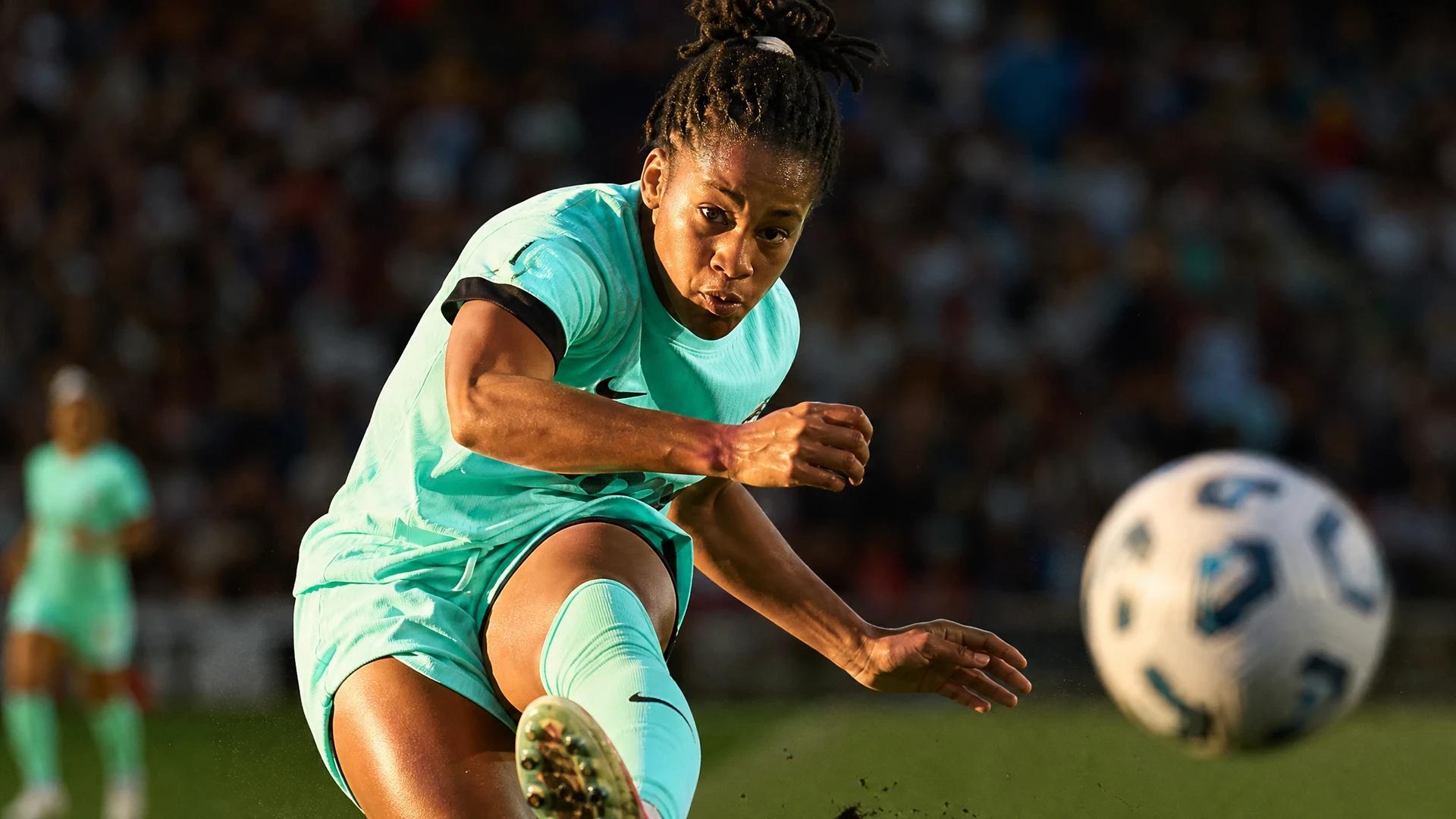 Close-up of a female soccer player kicking the ball during a match.