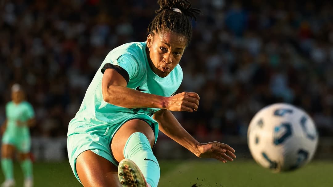 Close-up of a female soccer player kicking the ball during a match.