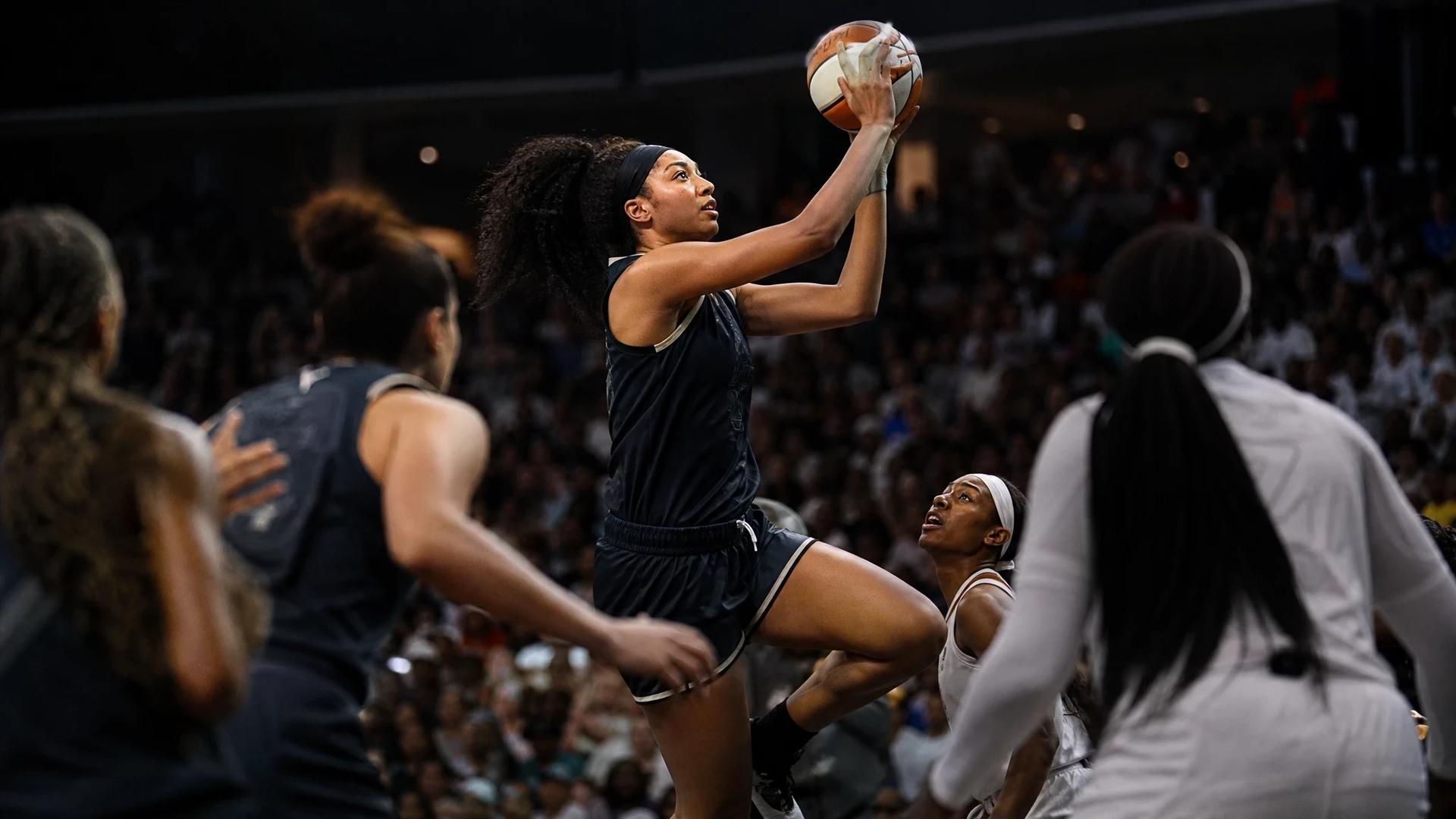 Shakira Austin in mid-air attempting a shot during a tense basketball game.