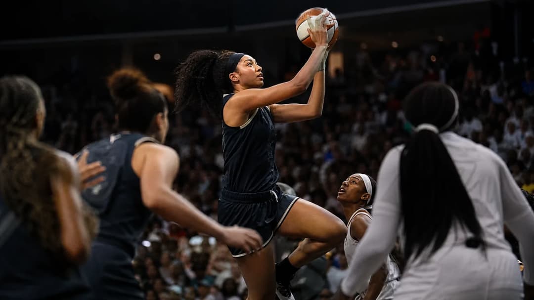 Shakira Austin in mid-air attempting a shot during a tense basketball game.