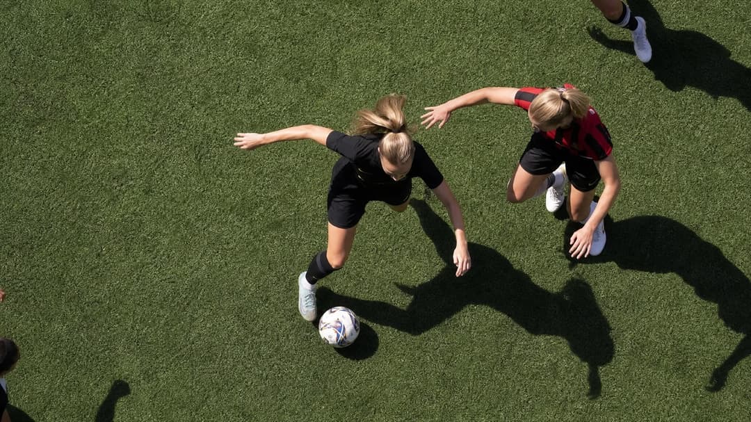 Aerial view of AIK midfielder Emilie Libakken Österås dribbling the ball on a football field.
