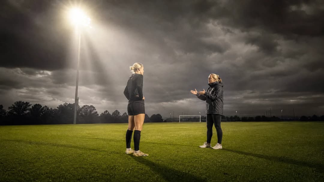 Jenna Nighswonger and coach Emma Coates interact on a training ground.