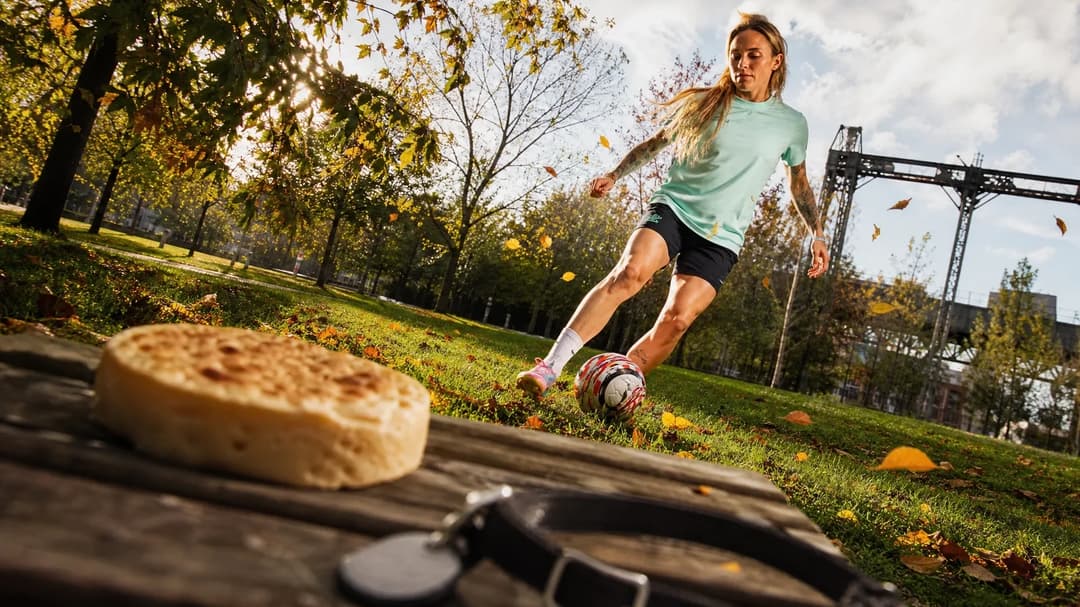 Mapi León practicing soccer in a London park with a crumpet and a cat collar in the foreground.