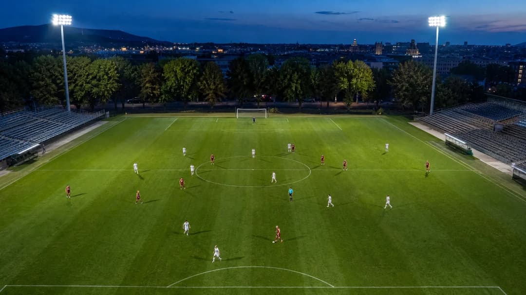 Aerial view of a football match at dusk, featuring players in action on the pitch.