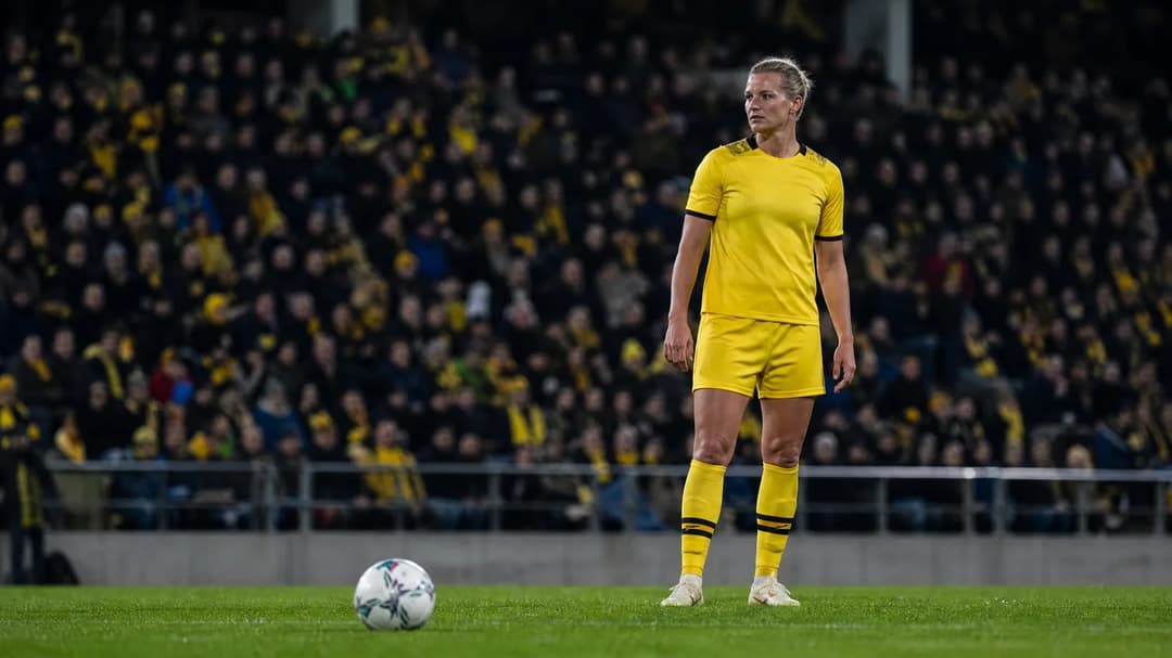 Alexandra Popp preparing to take a free kick in a football match at Stadion Rote Erde, surrounded by enthusiastic fans.