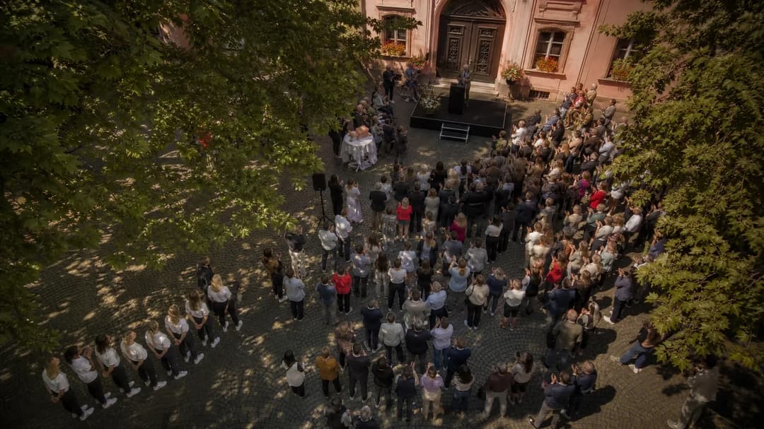Aerial view of a crowd at Mainz City Hall, with former players standing apart from the celebration.