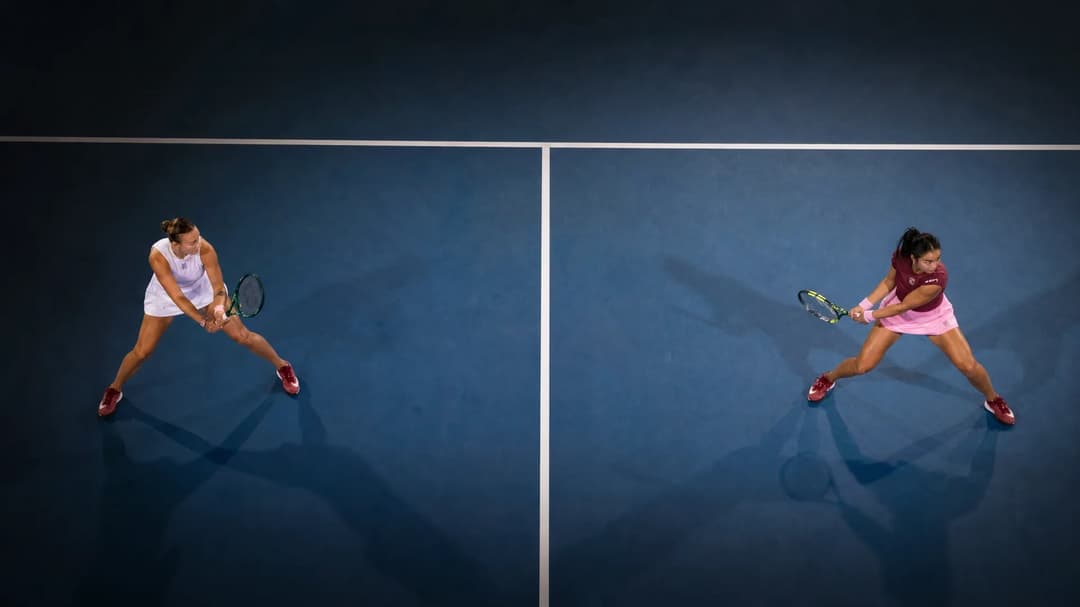 A bird's-eye view of two female tennis players preparing to serve, highlighting the anticipation before the match.