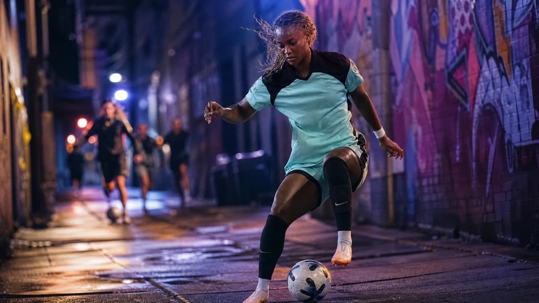 Jaedyn Shaw playing football in an urban setting with neon lights.
