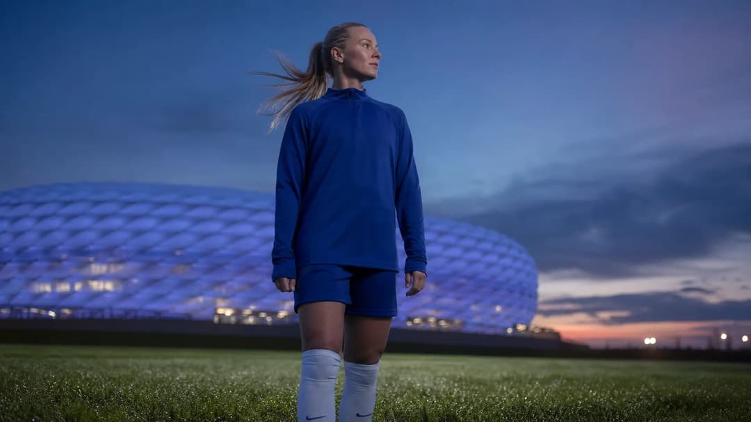 A low-angle shot of Hanna Glas standing in front of the Allianz Arena at dusk, reflecting on her departure to Kansas City.