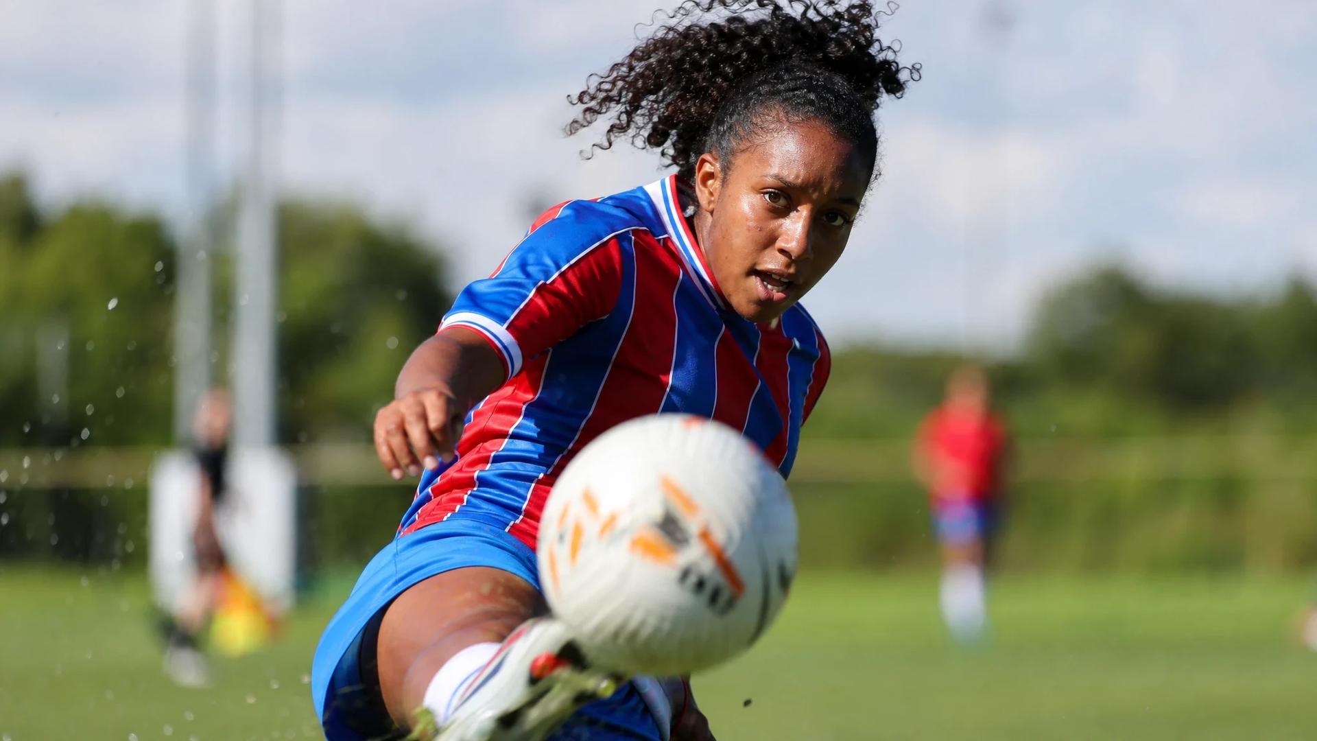 Close-up of Ashleigh Weerden focusing on kicking a soccer ball during training.