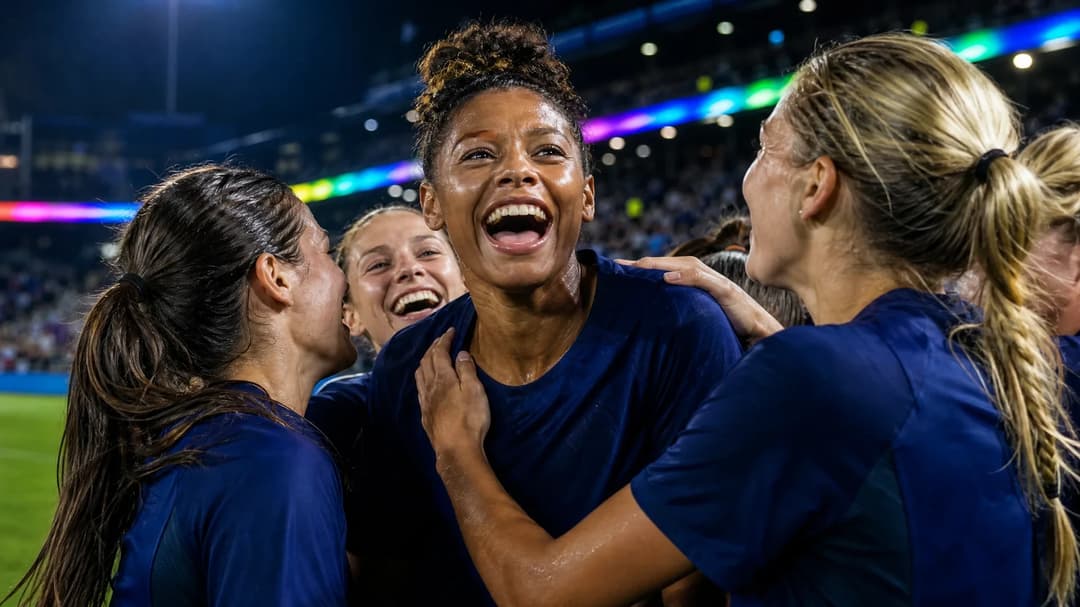 Caiya Hanks celebrating a goal with teammates in an urban stadium illuminated by neon lights.