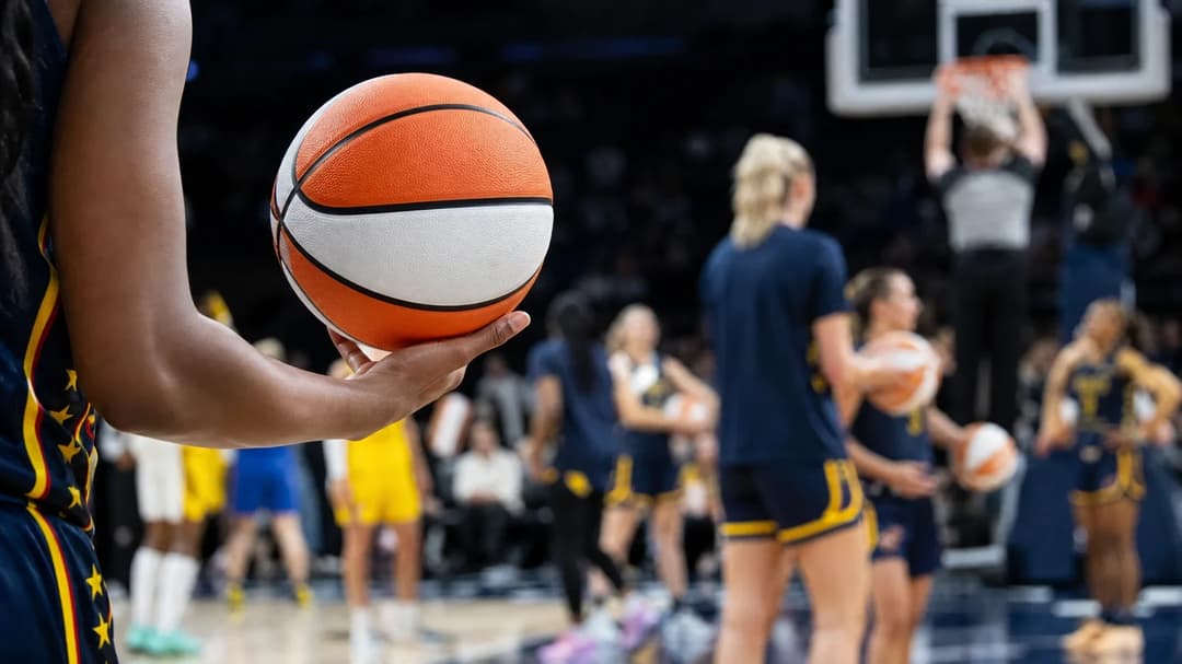 A close-up of a spinning basketball with players warming up in the background at the American Airlines Center.