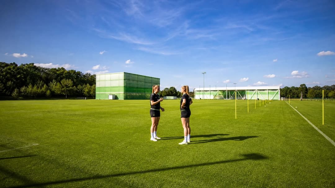 Mara Alber and a teammate interact on the training pitch while discussing strategy.