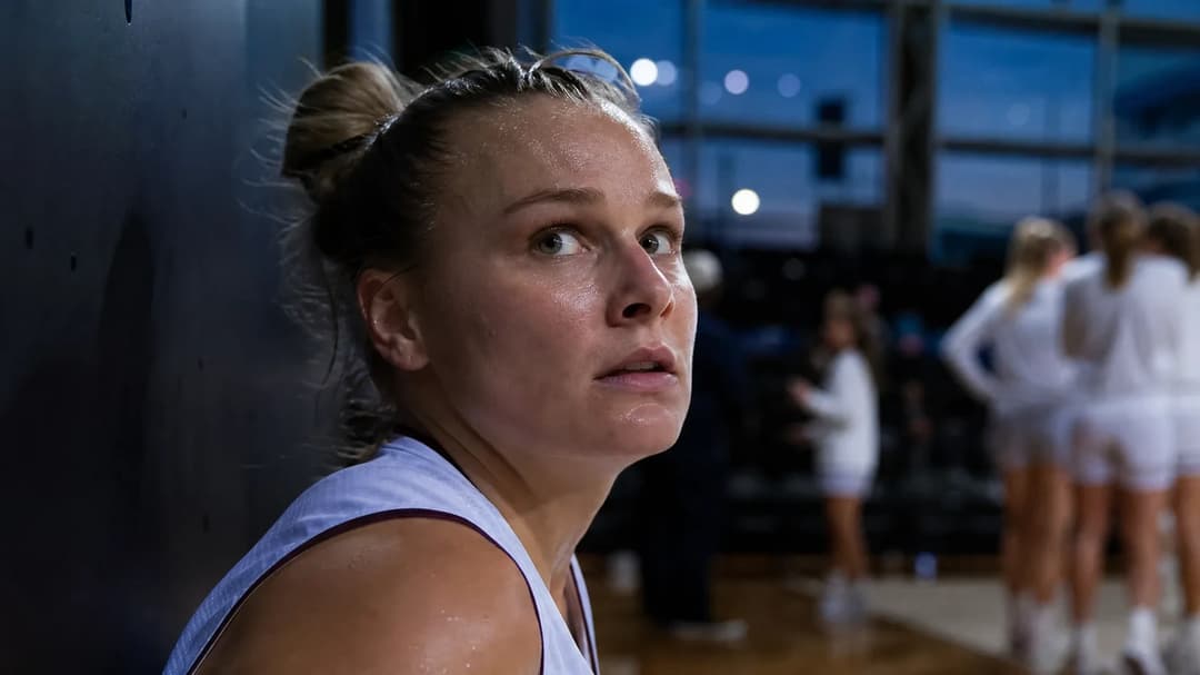Close-up of Isabelle Harrison reflecting after a basketball game, illuminated by soft blue light.