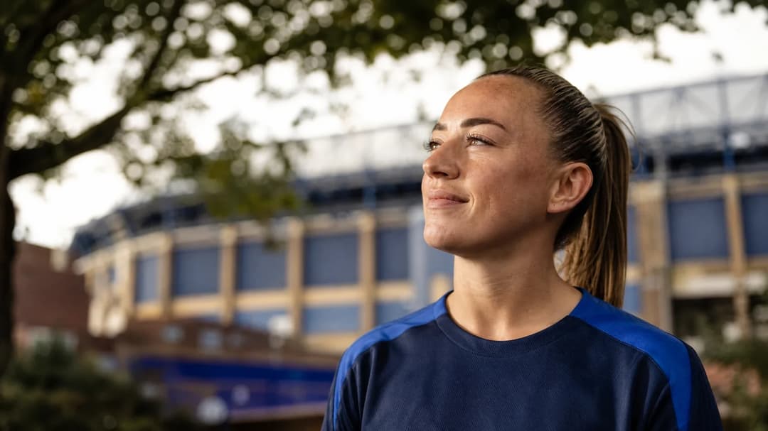 Katie McCabe standing outside Stamford Bridge, looking thoughtfully towards the stadium.