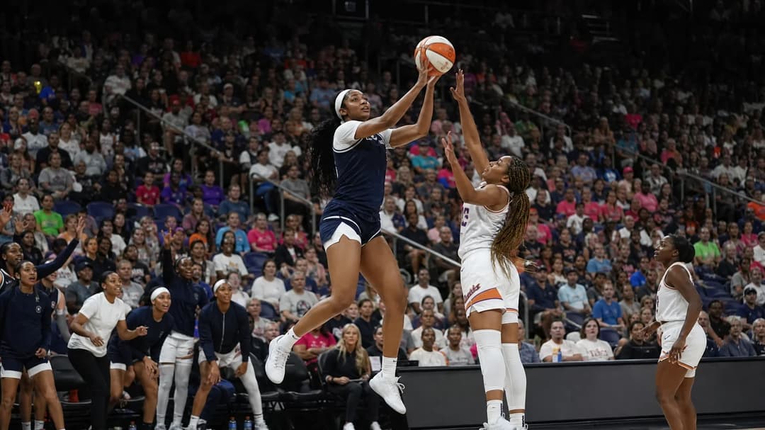 Basketball player Angel Reese leaps towards the hoop during a game, with a crowd and opposing players in the background.