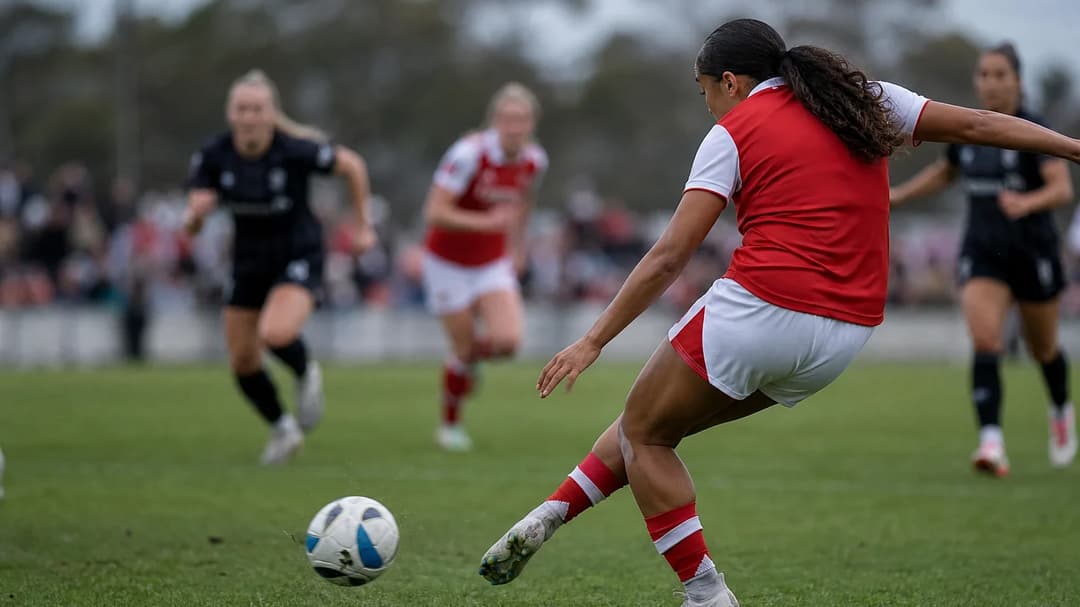 A close-up over-the-shoulder shot of Olivia Smith striking a football during a match.