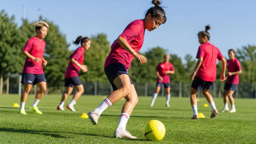 Japanese female football players practicing on a training field under the midday sun.