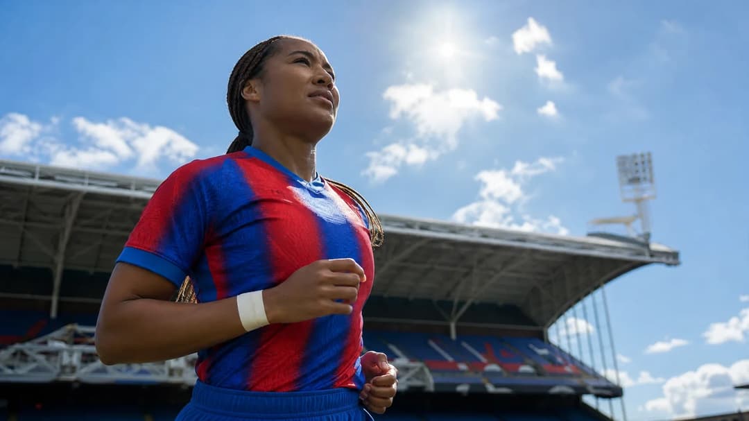 Lexi Lloyd-Smith, a football player, is silhouetted against a bright blue sky during midday sunlight.