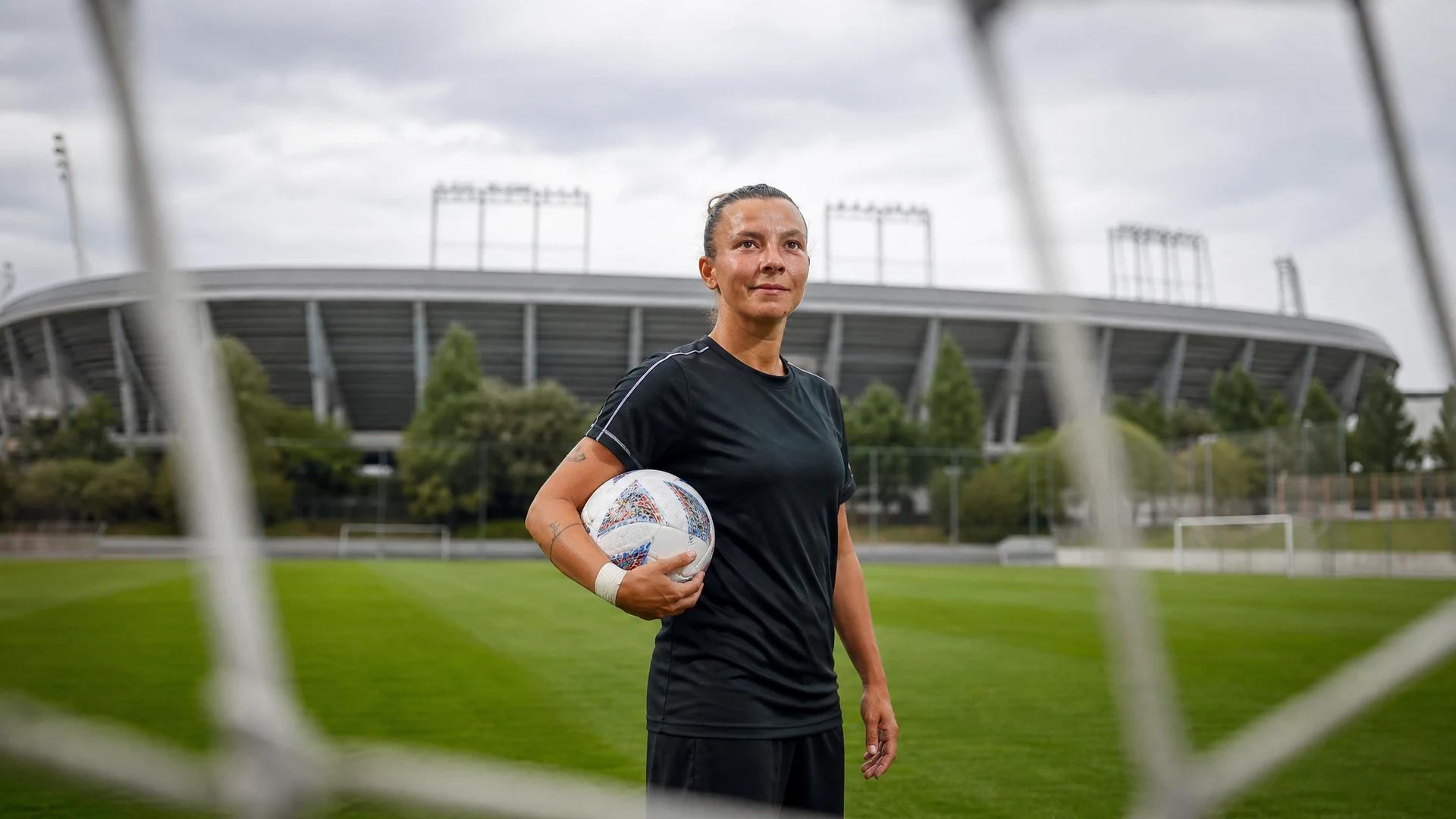 Arianna Caruso on a training pitch at Real Madrid's complex, holding a training ball with the stadium in the background.