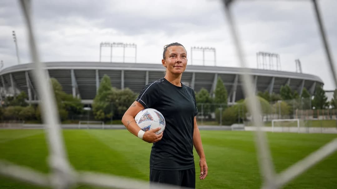 Arianna Caruso on a training pitch at Real Madrid's complex, holding a training ball with the stadium in the background.