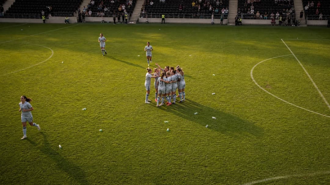 Bird's-eye view of a football pitch with players celebrating after a match.