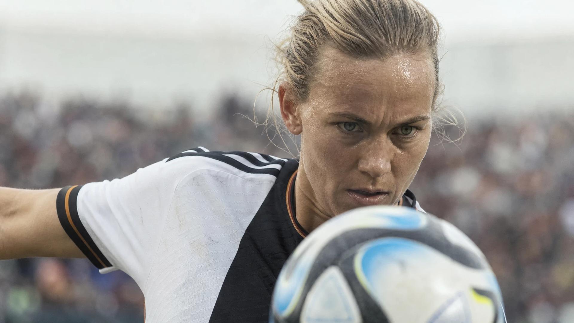 Close-up of a female football player in action, preparing to kick the ball.