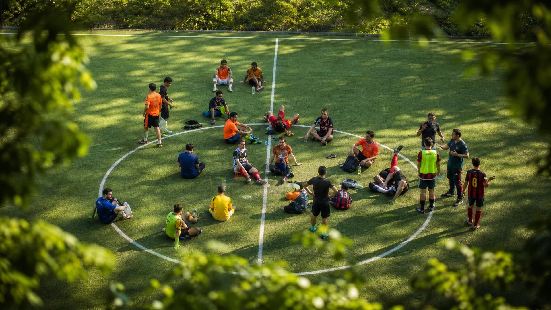 A bird's-eye view of a vibrant soccer field with players engaged in conversations post-match.