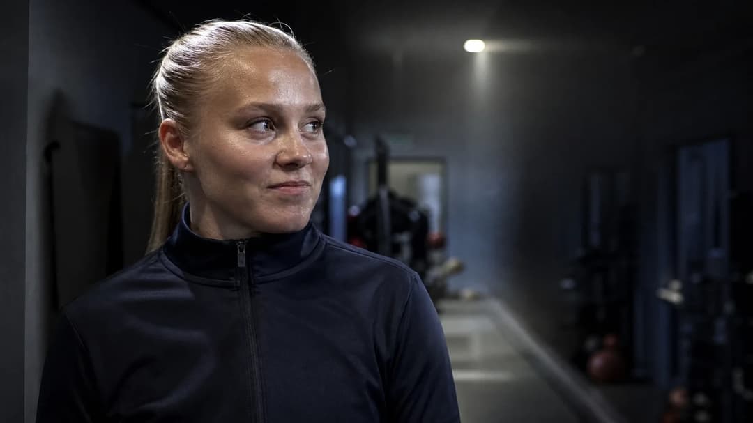 Emilie Libakken Österås in a training facility hallway, looking contemplative.