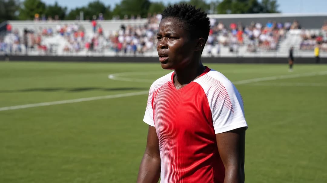 A female soccer player, Temwa Chawinga, stands on the field in an athletic pose, ready for the game.