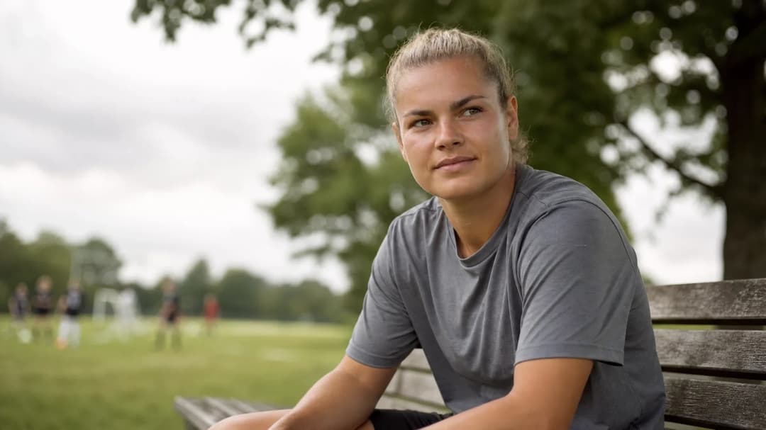 Kayleigh van Dooren sitting on a bench in a park, looking contemplative.