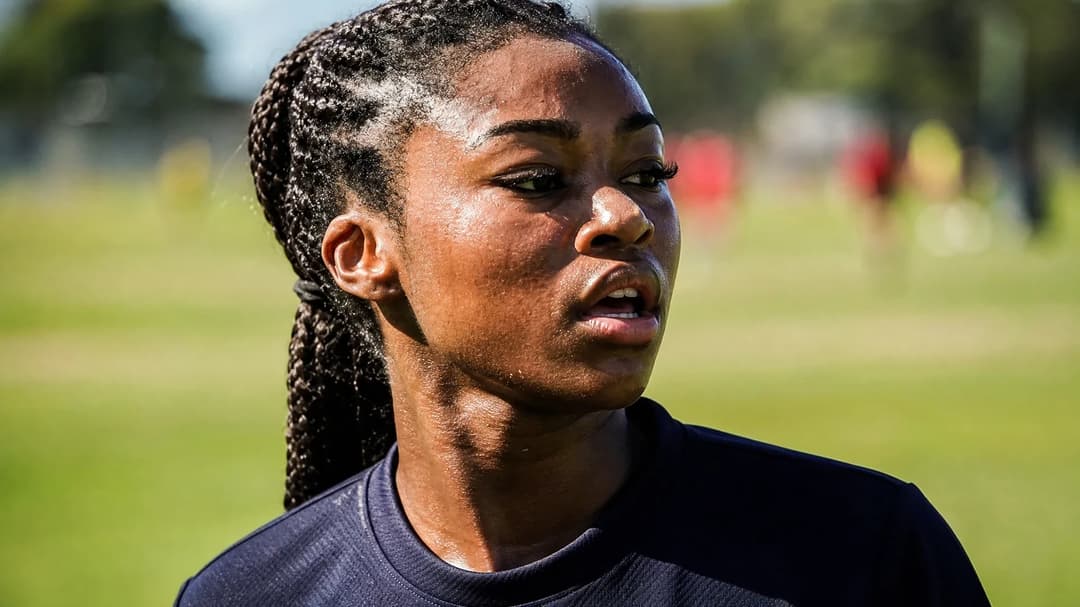 Close-up portrait of Monica Jusu Bah in Manchester United training kit, standing on a training pitch.
