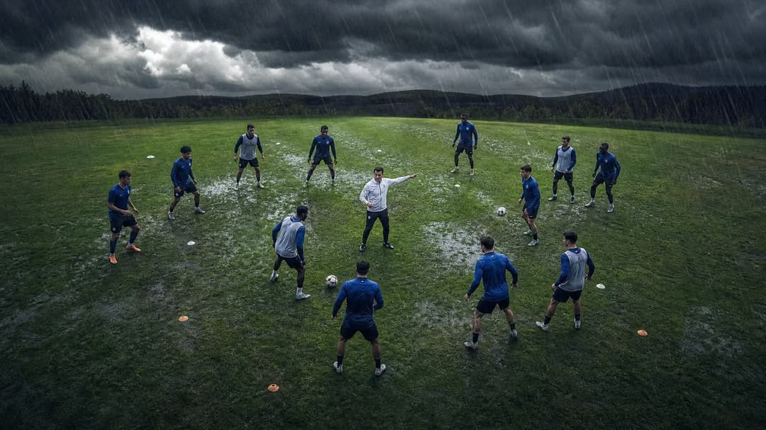 Arturo Ruiz directing players during a tactical drill on a stormy football pitch.