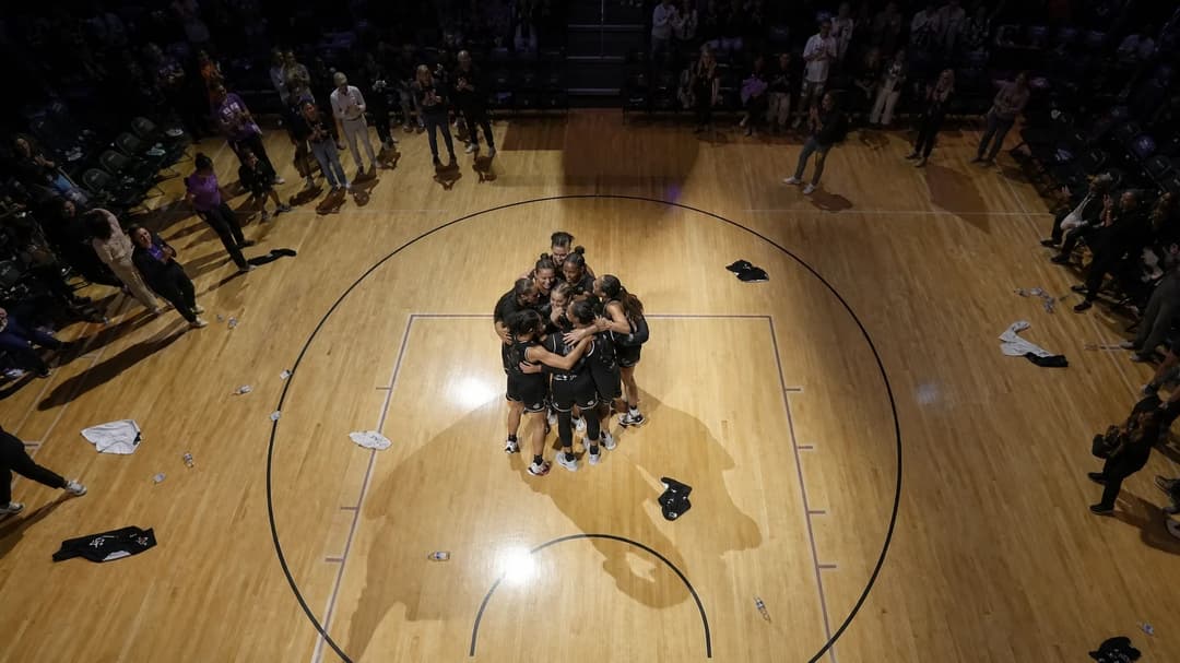A bird's-eye view of players celebrating in a basketball arena after a game.
