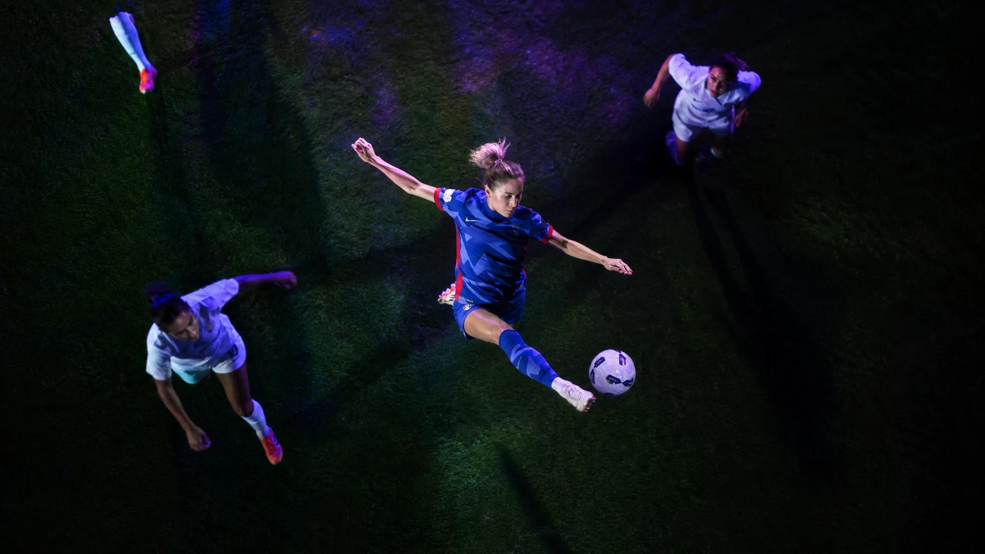 Bird's-eye view of Ashley Sanchez preparing to shoot during a football match, surrounded by neon lights.