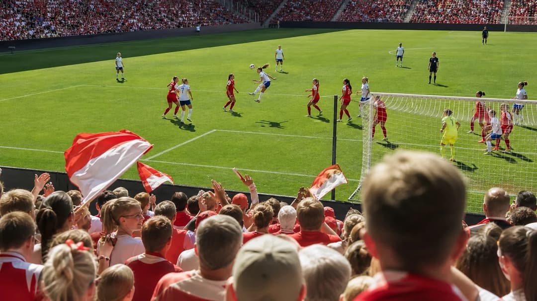 A wide shot of a football match at Dreisamstadion, showing enthusiastic fans and players in action.