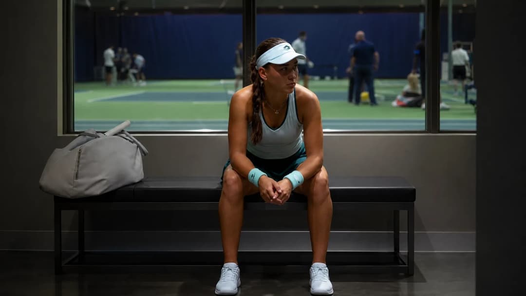 Kamilla Rakhimova sitting in the players' lounge of the US Open, looking pensive as she prepares for her match.